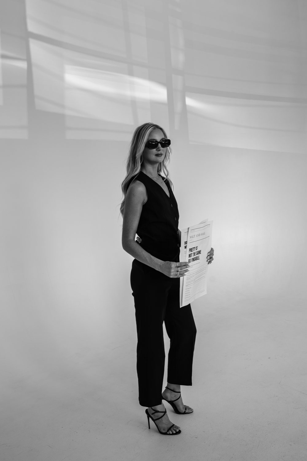 Sabrina holding the Salt and Sage newspaper, editorial web design for Denver wellness and beauty businesses